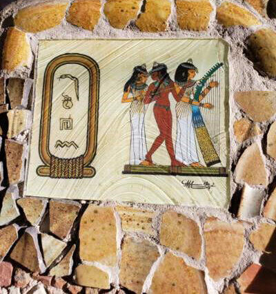 “A virtual mountain of stone and ceramic encases a photo of artwork originally performed with highly saturated watercolor paint on organic papyrus fabric. Depicted therein is a ‘Cartouche” spelling out my own name in hieroglyphs. This photo is also …
